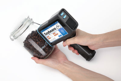 Handheld inkjet printer marking a label on a curved glass jar