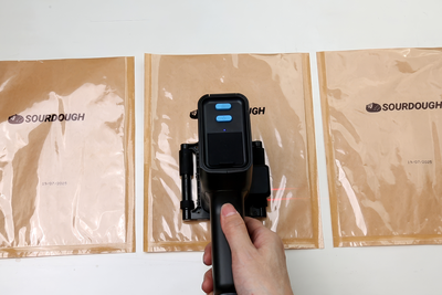 Laser-guided date code printer marking sealed food packaging bags